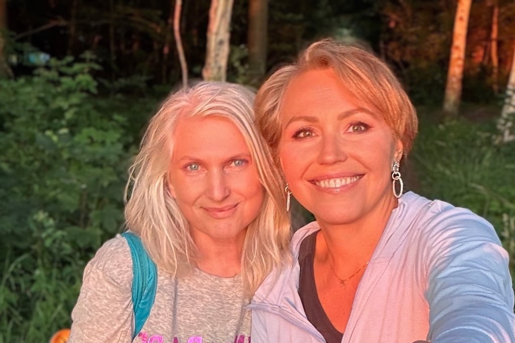 Two smiling women in nature at sunset, glowing with warmth, friendship, and joyful connection.