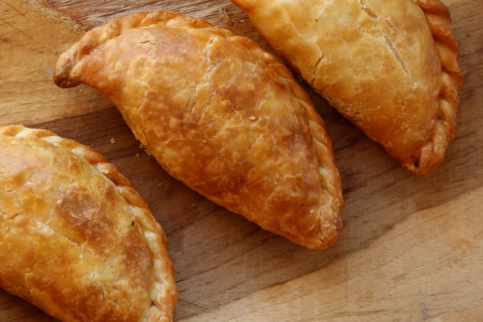 a wooden cutting board with three pastries on a cutting board
