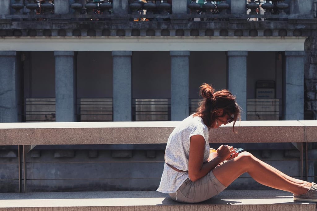 A Woman Sitting on Concrete Bench in Front of a Building in Ljubljana