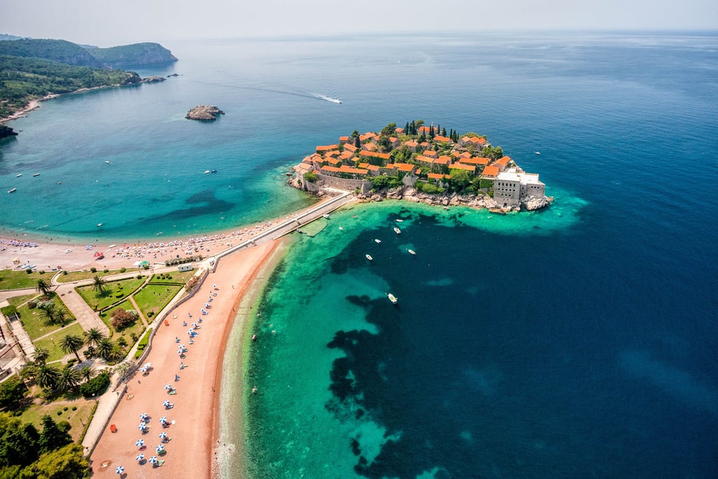 Aerial view of Sveti Stefan island resort and pink sand beach on the Adriatic coast in Montenegro.