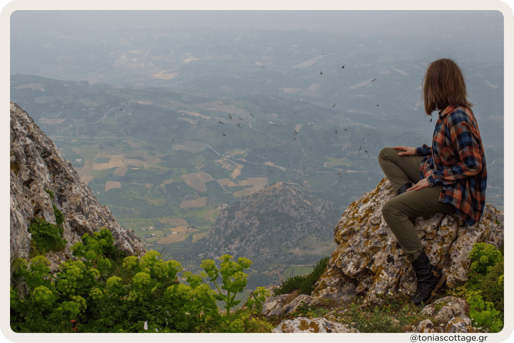 Woman sitting with a view of the valley in the mountains of Crete, surrounded by nature