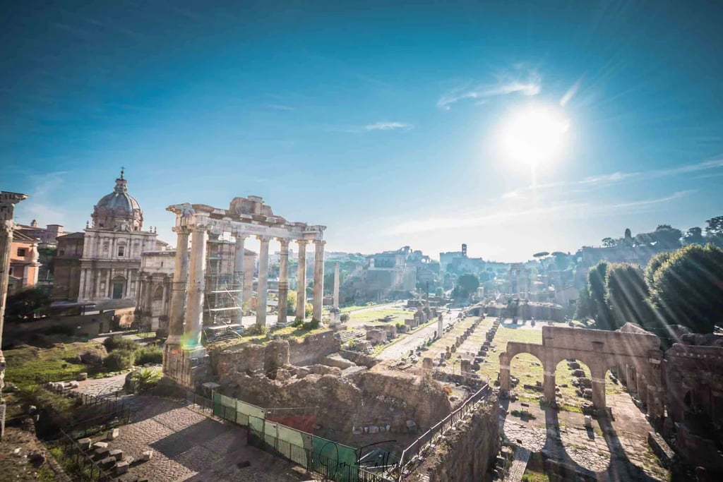 Panoramic view of the Roman Forum ruins in Rome under a bright sunny sky.