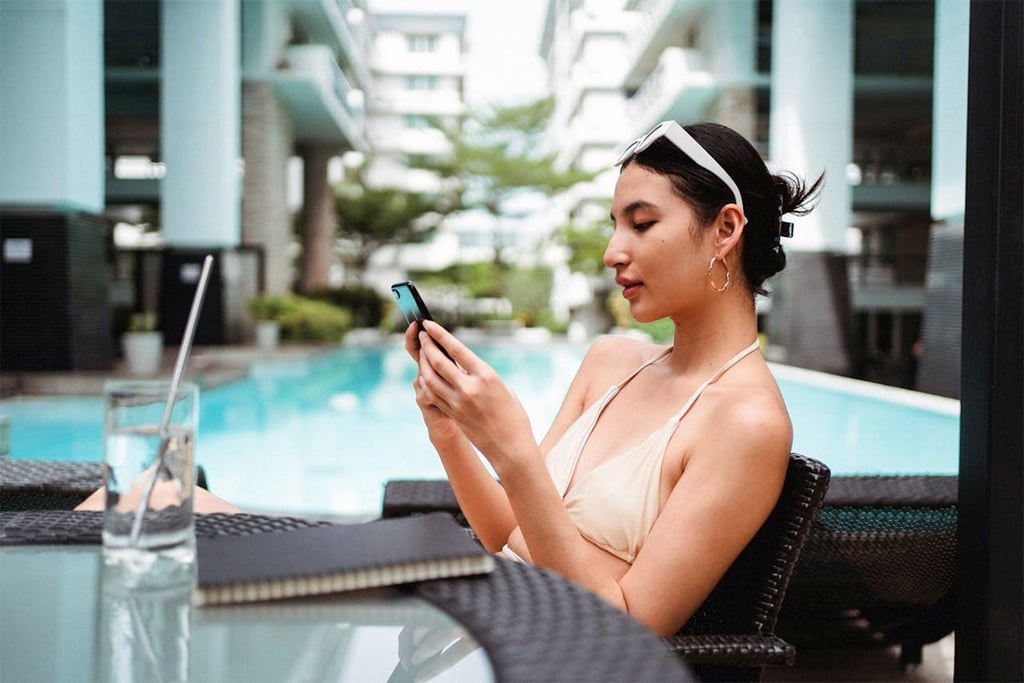 Lady using mobile phone at hotel swimming pool