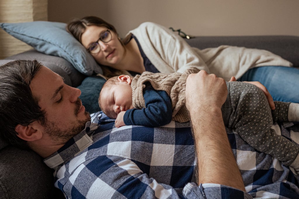 Baby liegt auf dem Papa, die Mama betrachtet die beiden