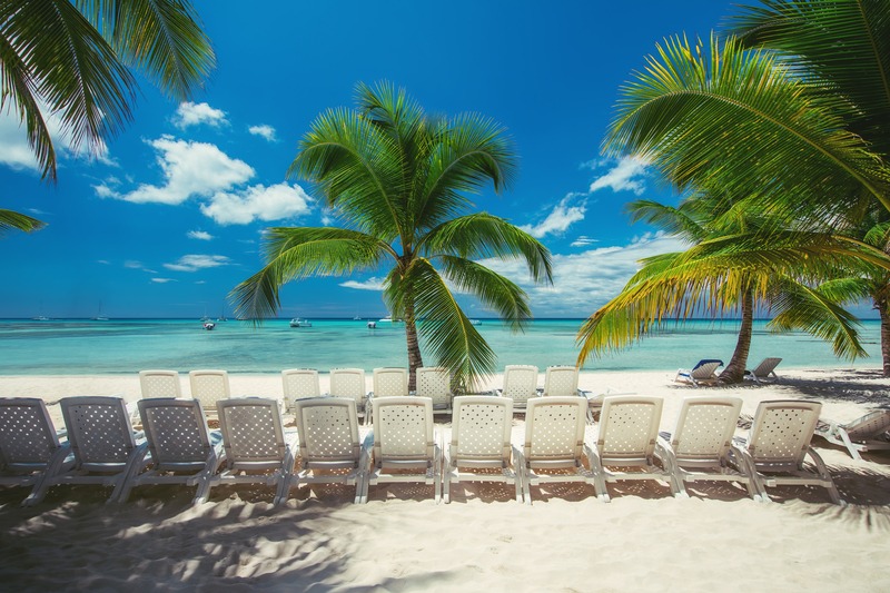 Beach chairs under palm trees on Saona Island with white sand and turquoise Caribbean water