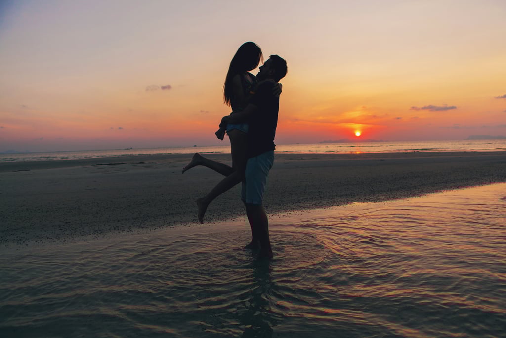 a man and woman kissing on the beach during a sunset on their honeymoon in the dominican republic