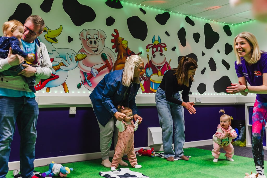 a group of parents, dancing with their children in moo music class. 