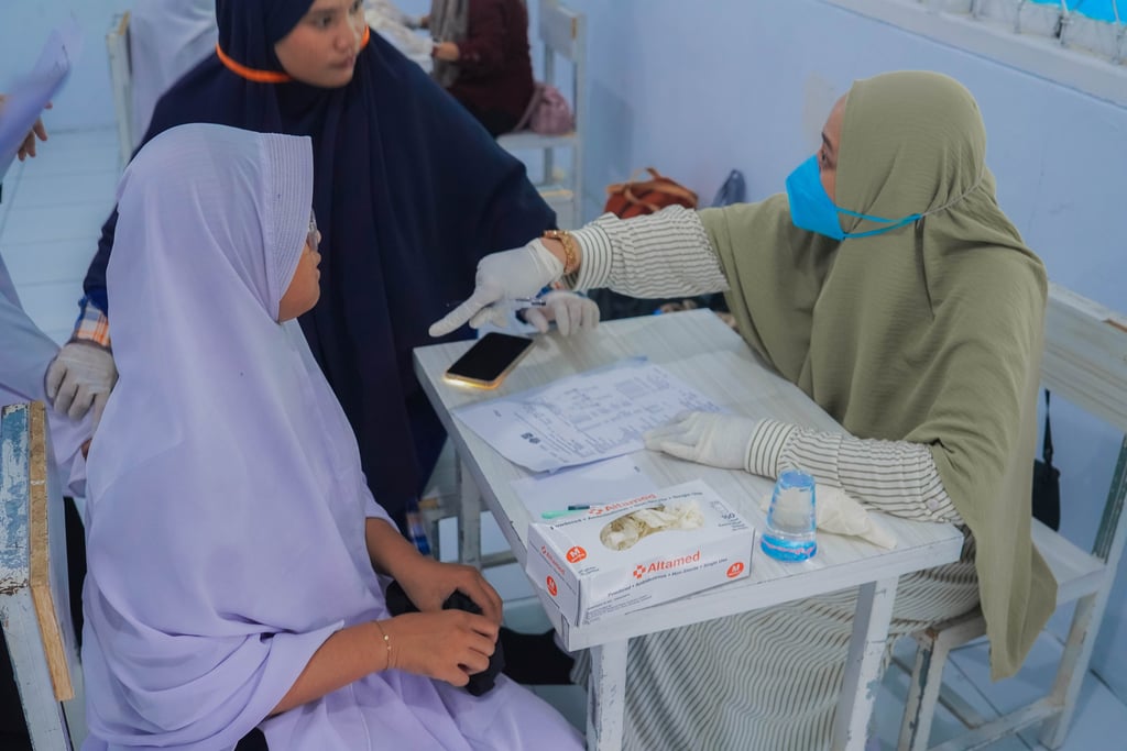Tenaga kesehatan memberikan edukasi kesehatan kepada masyarakat dalam program layanan kesehatan komu