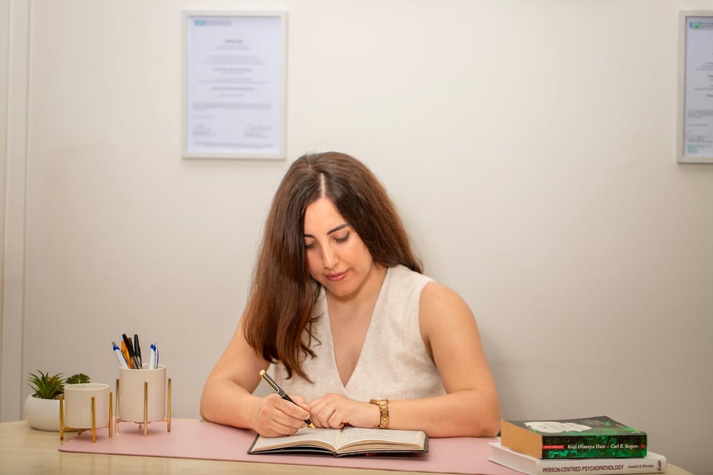 Psychotherapeutin Linda Acikalin sitzt am Schreibtisch und macht Notizen in ihrer Praxis.