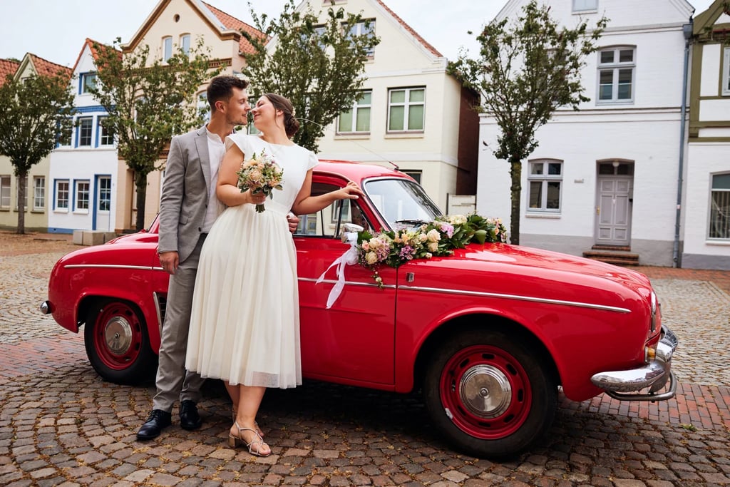 Close-up of a pink rose boutonniere on a groom's navy blue wedding suit jacket.
