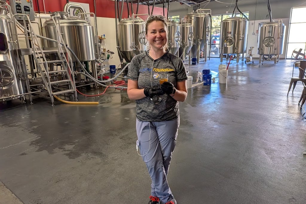 a woman standing in front of brewing tanks