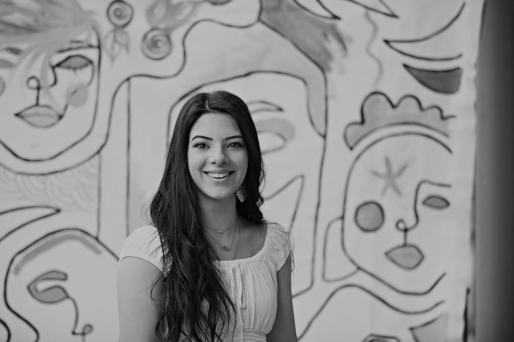 a woman in a white dress standing in front of a wall with a mural of