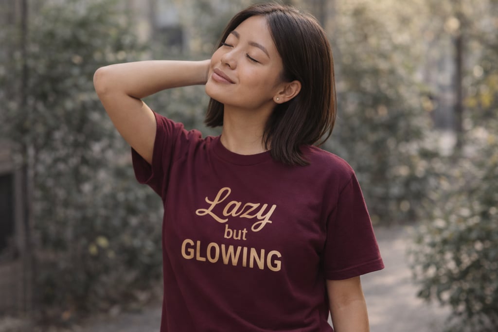 Frau mit maroon „Lazy but Glowing“ Shirt steht entspannt draußen. Symbol für bewusst langsamer leben