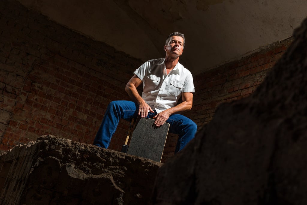 Schlagzeuger sitzt mit geschlossenen Augen auf einem Cajon und vertieft sich konzentriert in den Gro