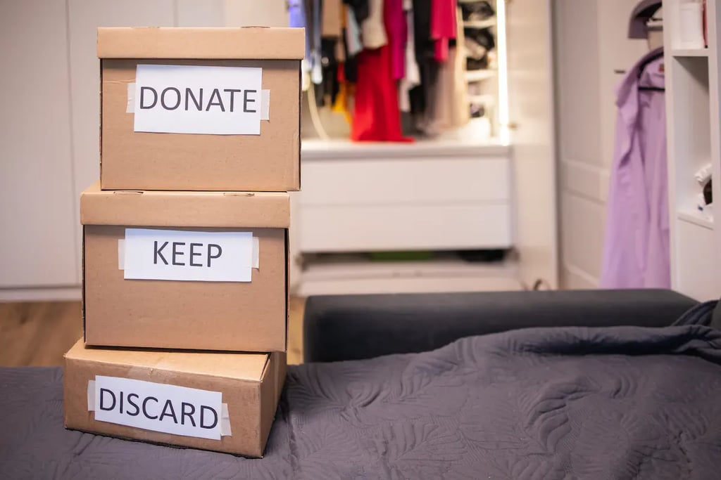 Stacked cardboard boxes labeled donate, keep, and discard for closet organization and decluttering.