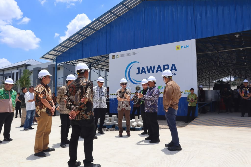 Officials in hard hats visiting the JAWARA PLN industrial facility for a sustainable energy project inspection.