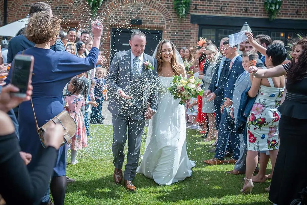 newly-wed running through confetti being thrown by guests