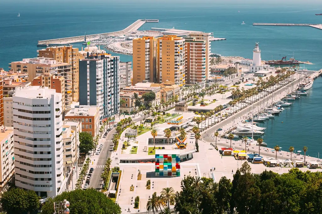 Vista del puerto de Málaga con paseo marítimo, edificios residenciales y el faro de La Farola