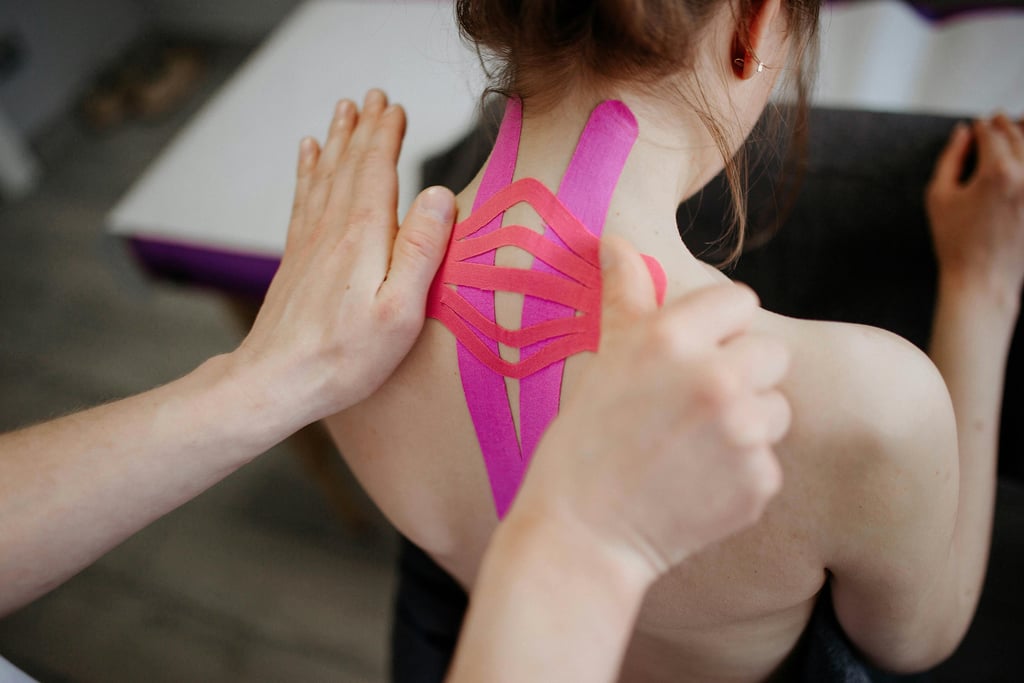 “Physiotherapist applying kinesiology tape to upper back.”