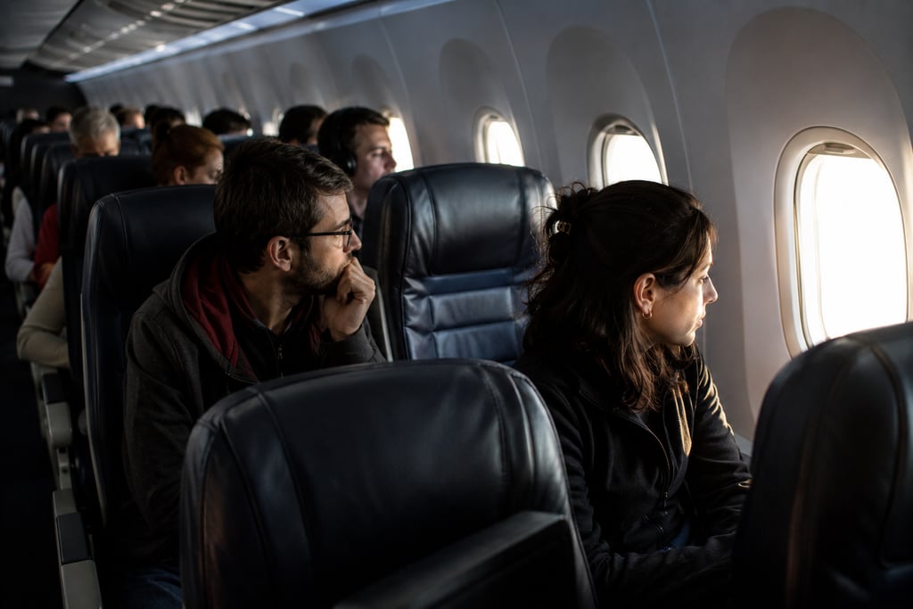 Passengers looking out window during a commercial flight inside an airplane cabin.