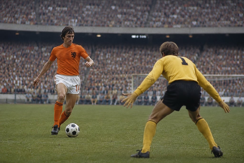 Johan Cruyff dribbles a soccer ball toward a goalkeeper during a historic match for the Netherlands.
