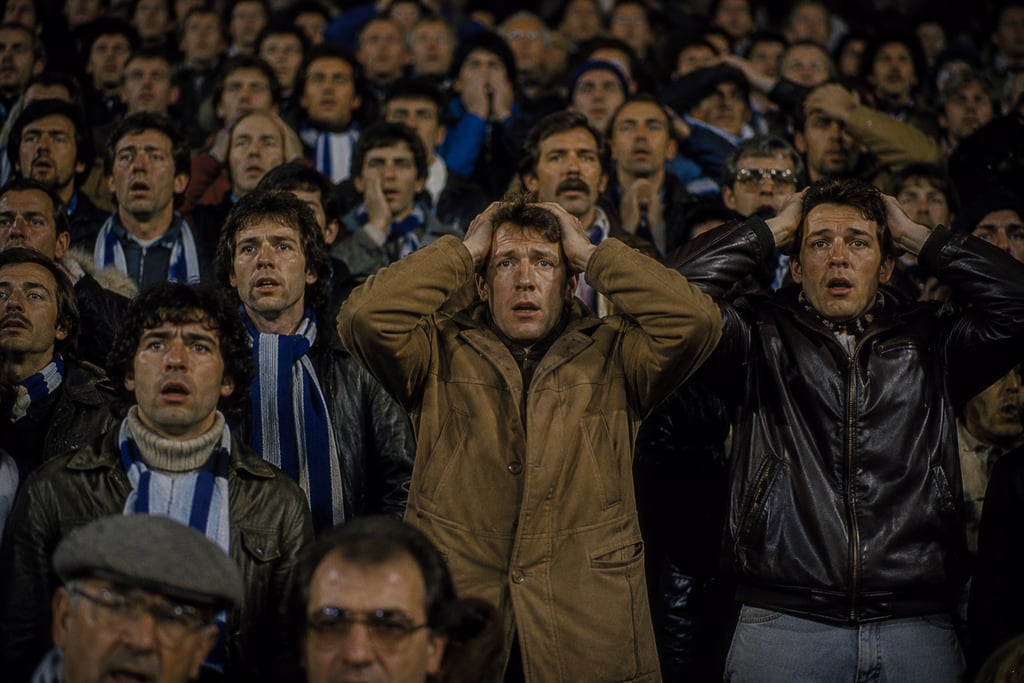Devastated football fans with hands on heads reacting to a loss in a crowded stadium crowd.