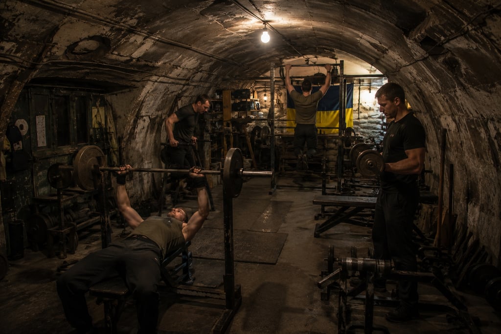 Men training in an underground bunker gym with weights and a Ukrainian flag.