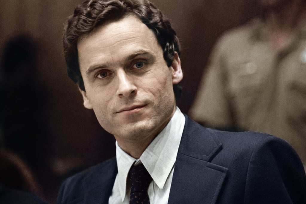 A colorized close-up portrait of Ted Bundy in a courtroom wearing a navy suit and tie.