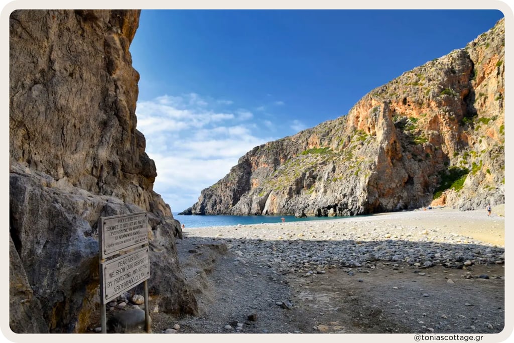 Agiofarrago Gorge in Crete, with high rocky walls, some trees, and a quiet beach meeting the sea