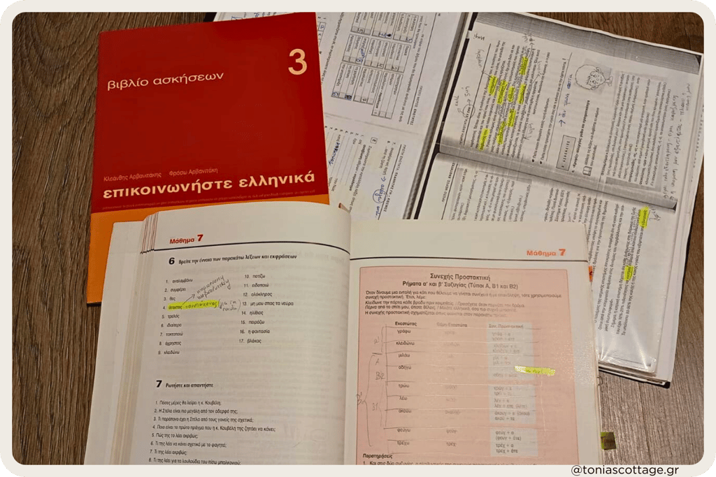 Greek language exercise books and study notes laid out on a table