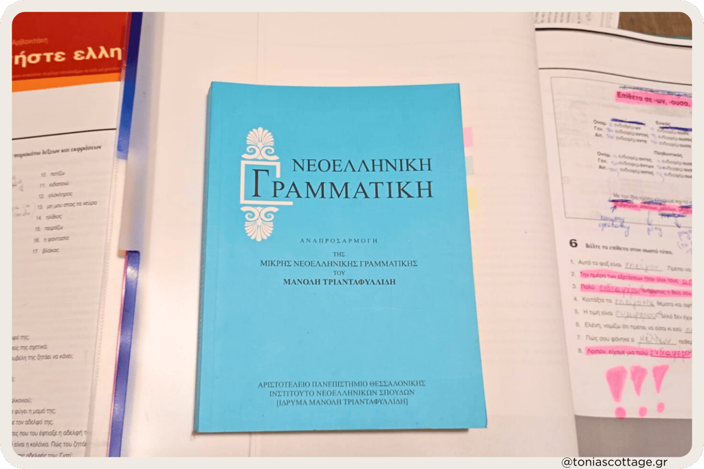 Greek language exercise books and study notes laid out on a table