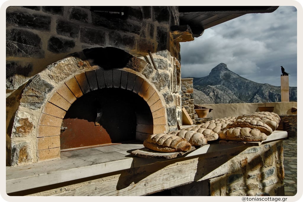 Loaves of bread cooling by a stone oven, with Asterousia mountains in the background.