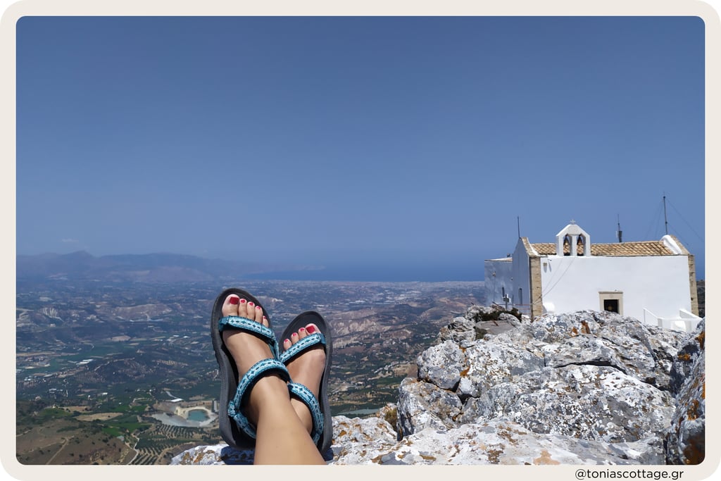 Summer on Mount Juktas: feet in sandals resting above a chapel and vast Cretan valley view