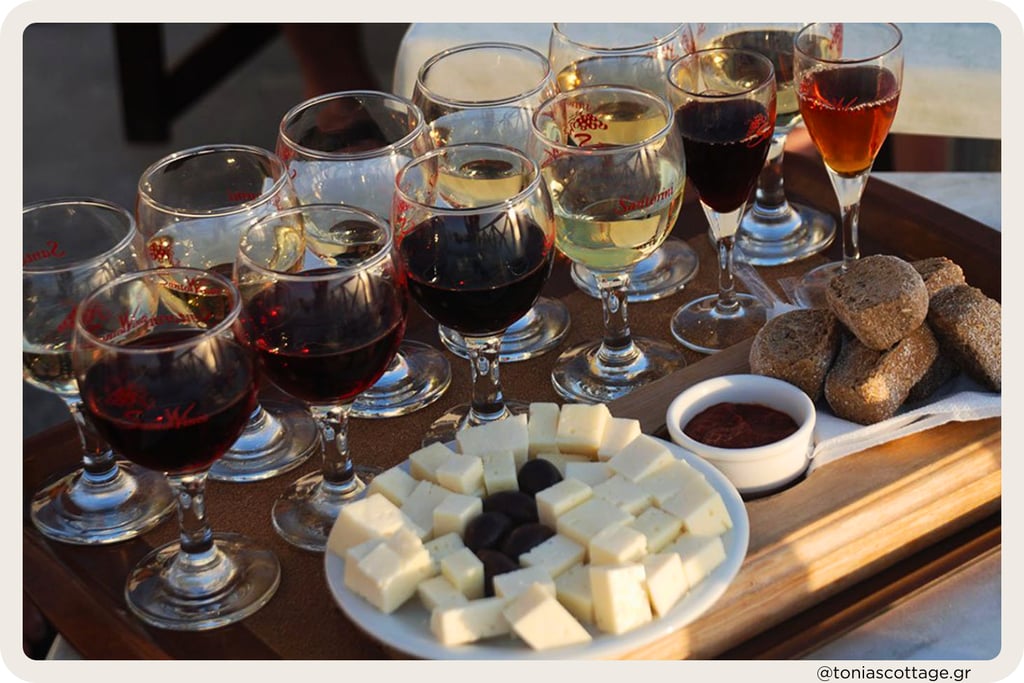 Wine glasses with red and white wines, served with cheese, olives, rusks, and dip on a tray