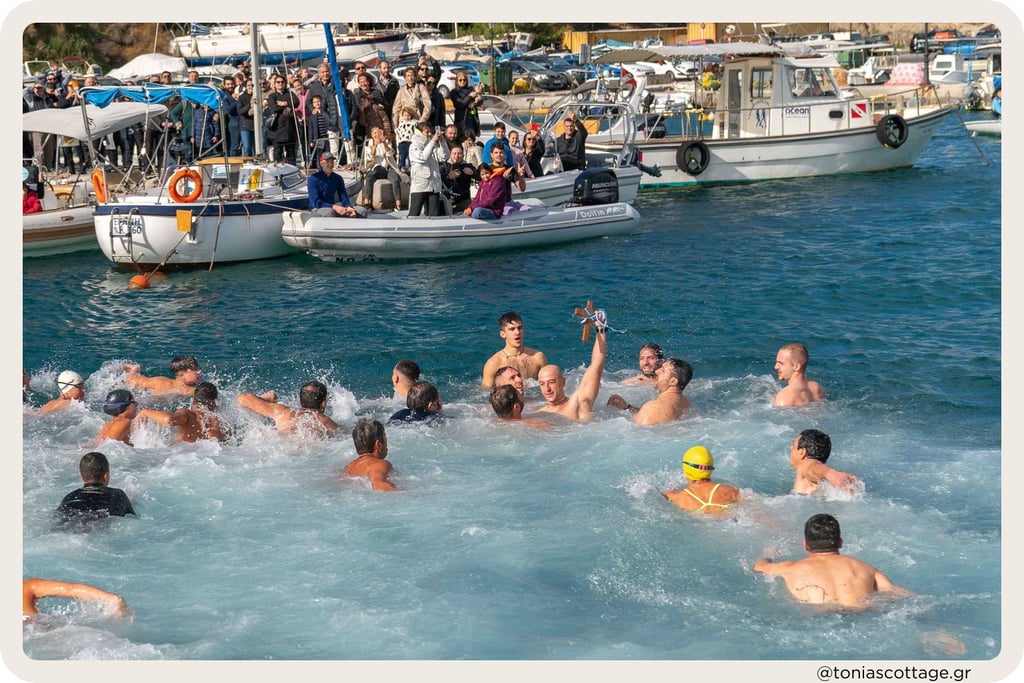 Swimmers in the sea during Epiphany, with people watching from boats in the harbor of Crete