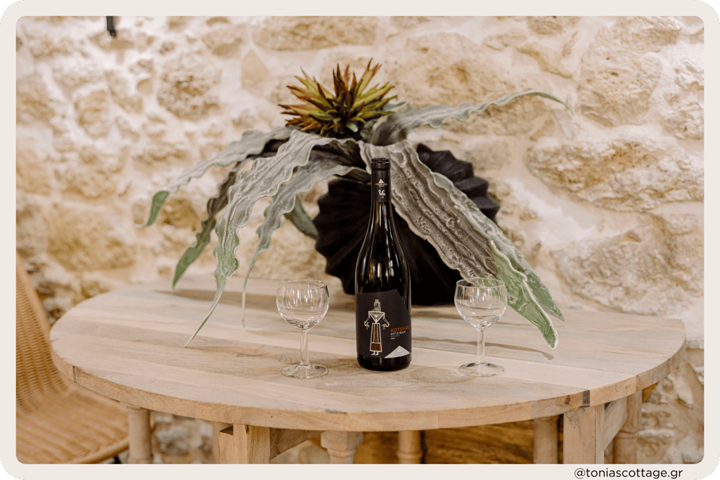 Table at Tonia's Cottage with a bottle of Lyrarakis wine and two glasses, set for a relaxing moment