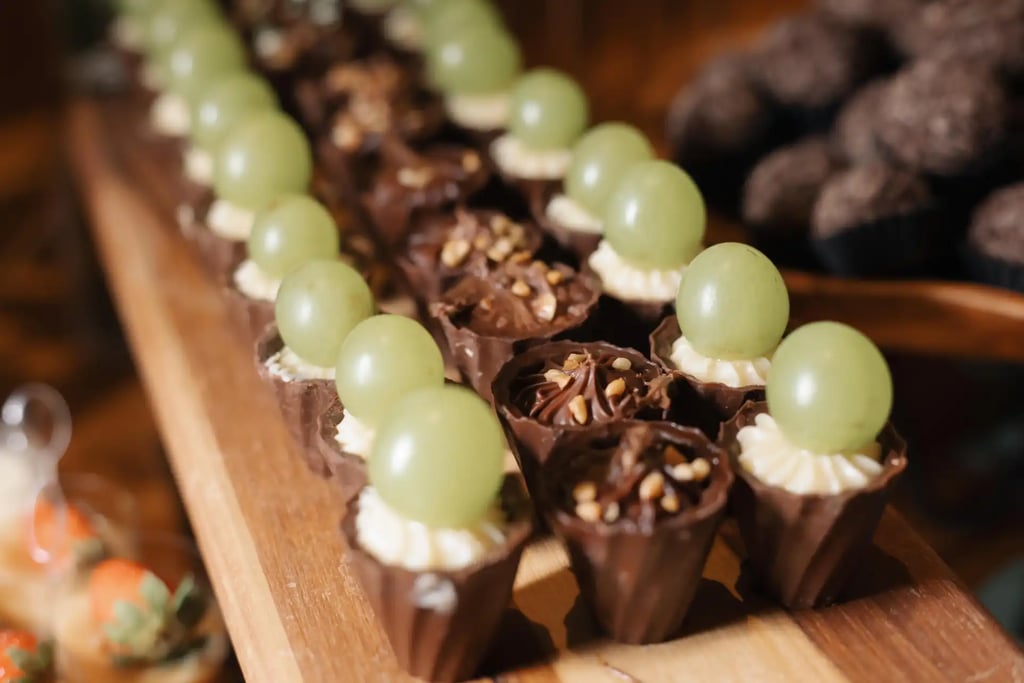 Imagem de deliciosos doces decorados com uvas verdes e cobertura de chocolate, perfeitos para festas