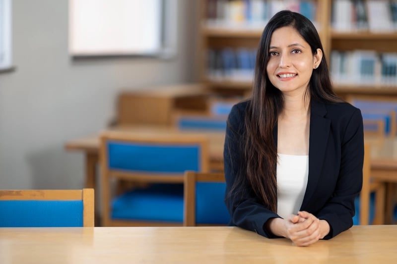 Dr Anam in black suit in library