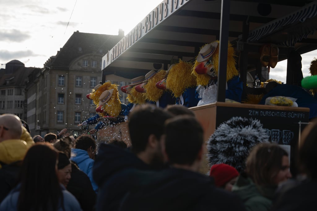 Fasnachtsclique mit bunten Kostümen auf Wagen in der Basler Innenstadt