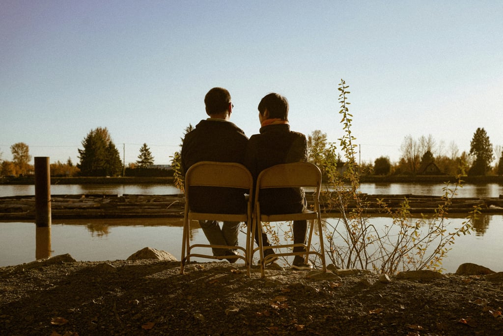 Male couple looking out at a lake concerned about their couples relationship