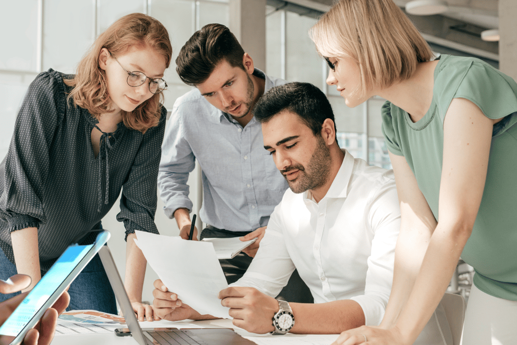 a group of people standing around a laptop computer