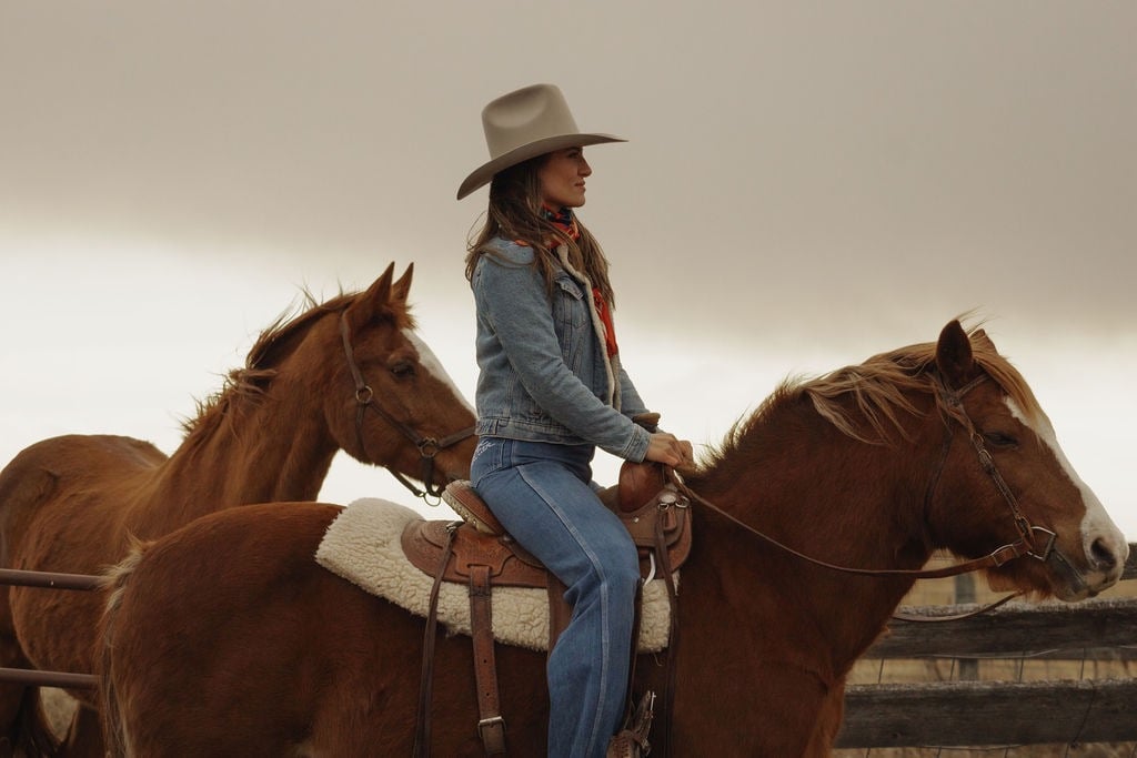 a woman in a cowboy hat riding a horse