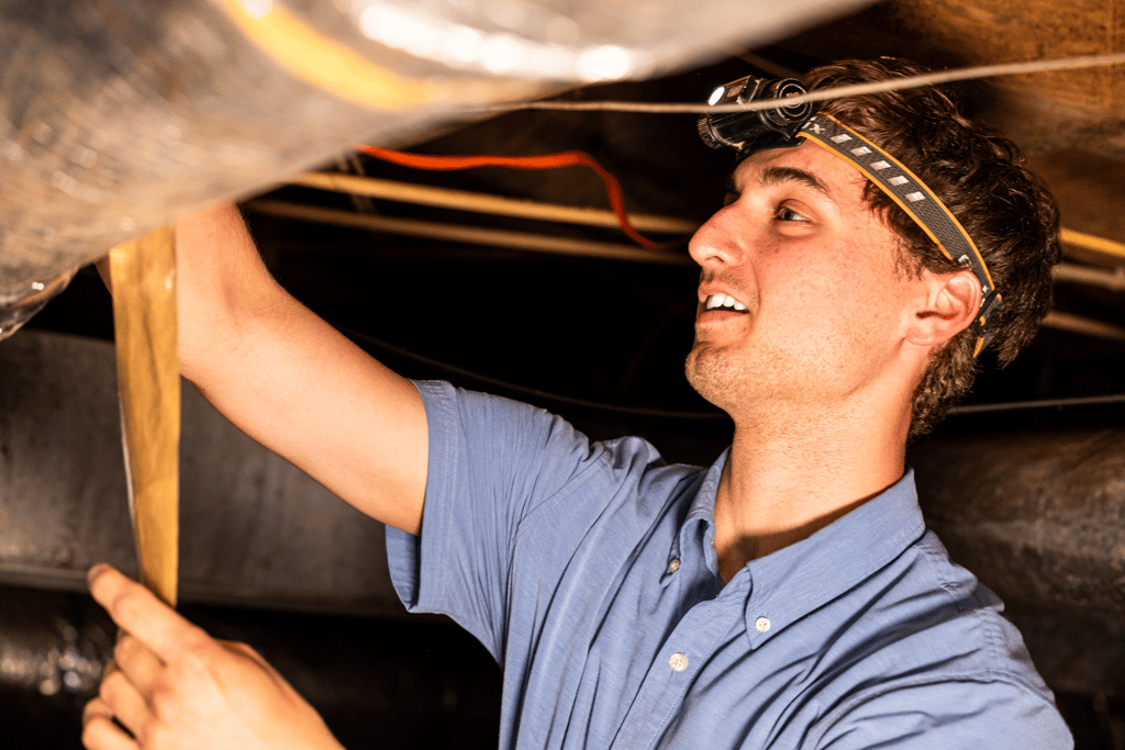 Jayden Kelly doing maintenance work in a crawlspace