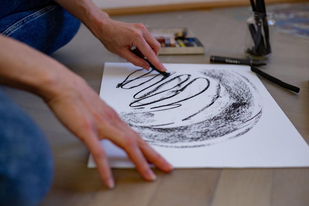 eine Person die mit Kohle auf Papier gestaltet.