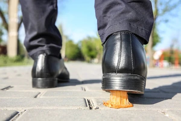 Man walking on a sidewalk with gum stuck to the bottom of his shoe