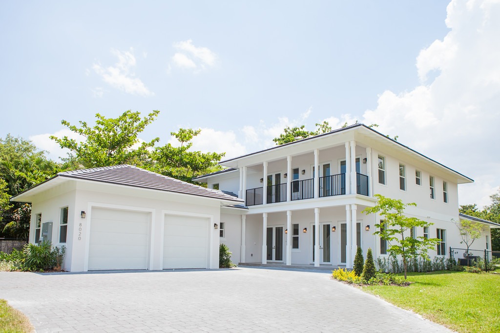 a white luxury home with a large driveway shown and a two door garage