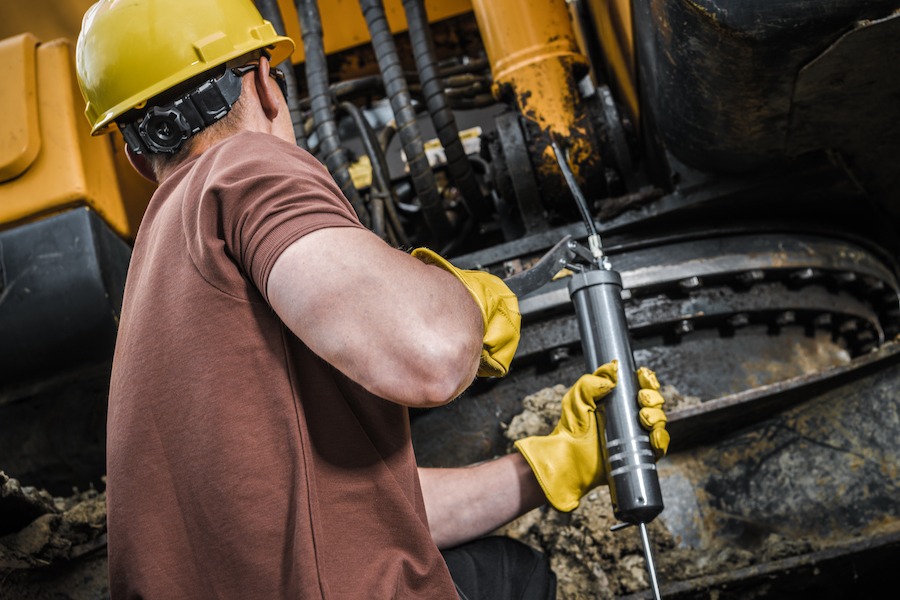 A man greasing his equipment using Grease Dispensers to properly Lubricate his machineries