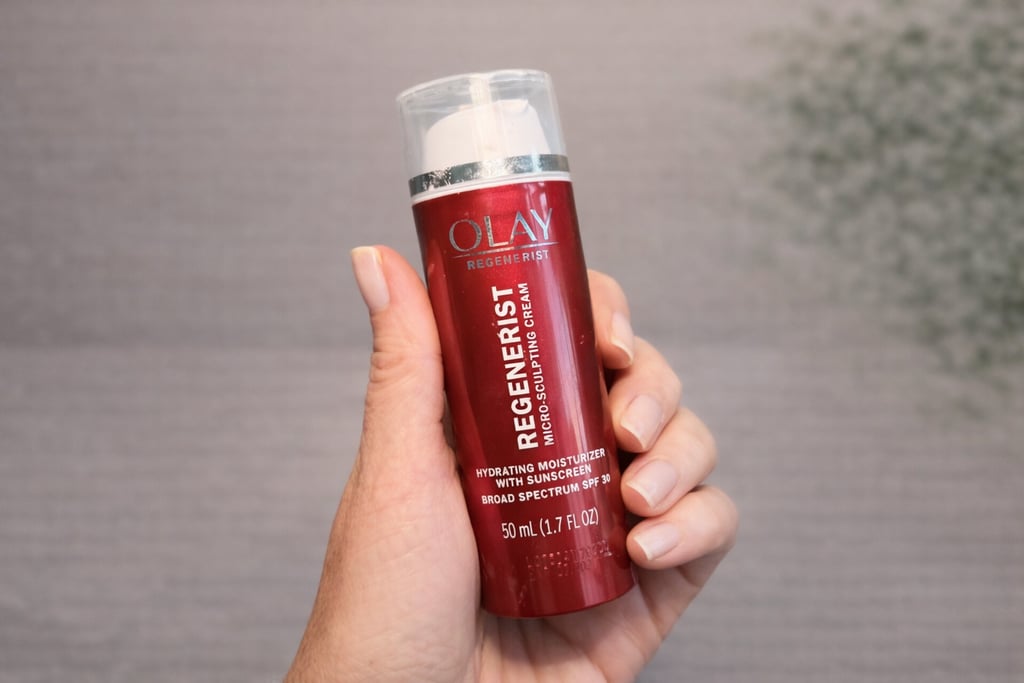 Hand holding Olay Regenerist Micro-Sculpting Cream with SPF for hydrating anti-aging skincare