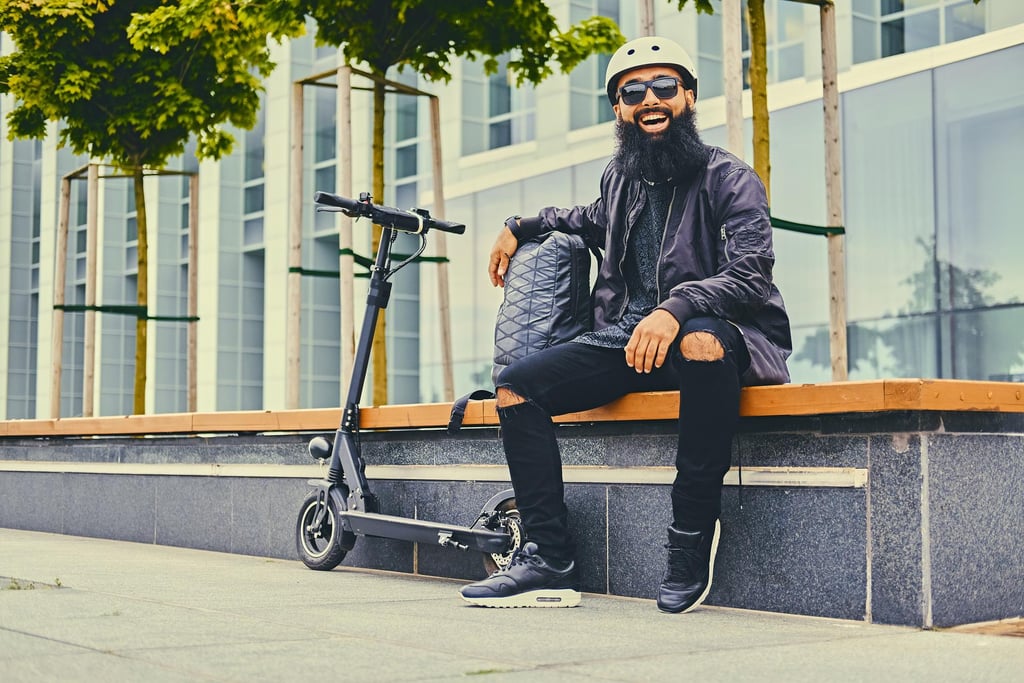 a man with a beard and a beard sitting on a bench with an electric scooter