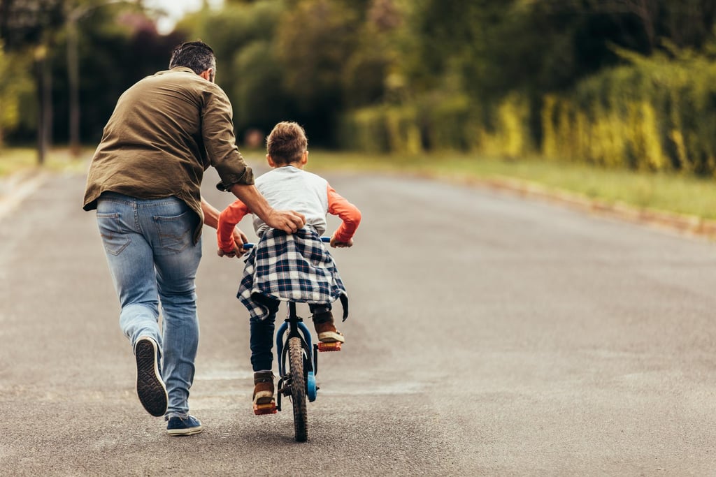 a man and a child riding bikes on a road